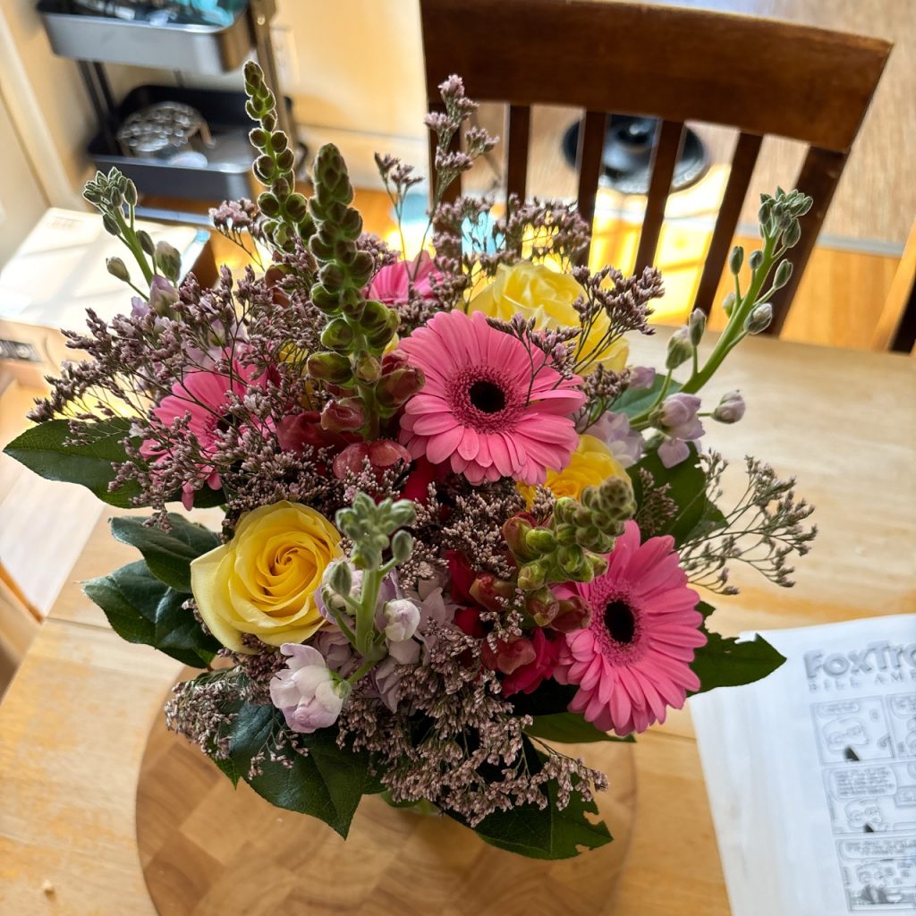 A gorgeous bouquet of pink daisies, yellow roses, and some kind of long white-purple flower that I don't know, and some purple filler. I'm bad at flower names but it's beautiful.